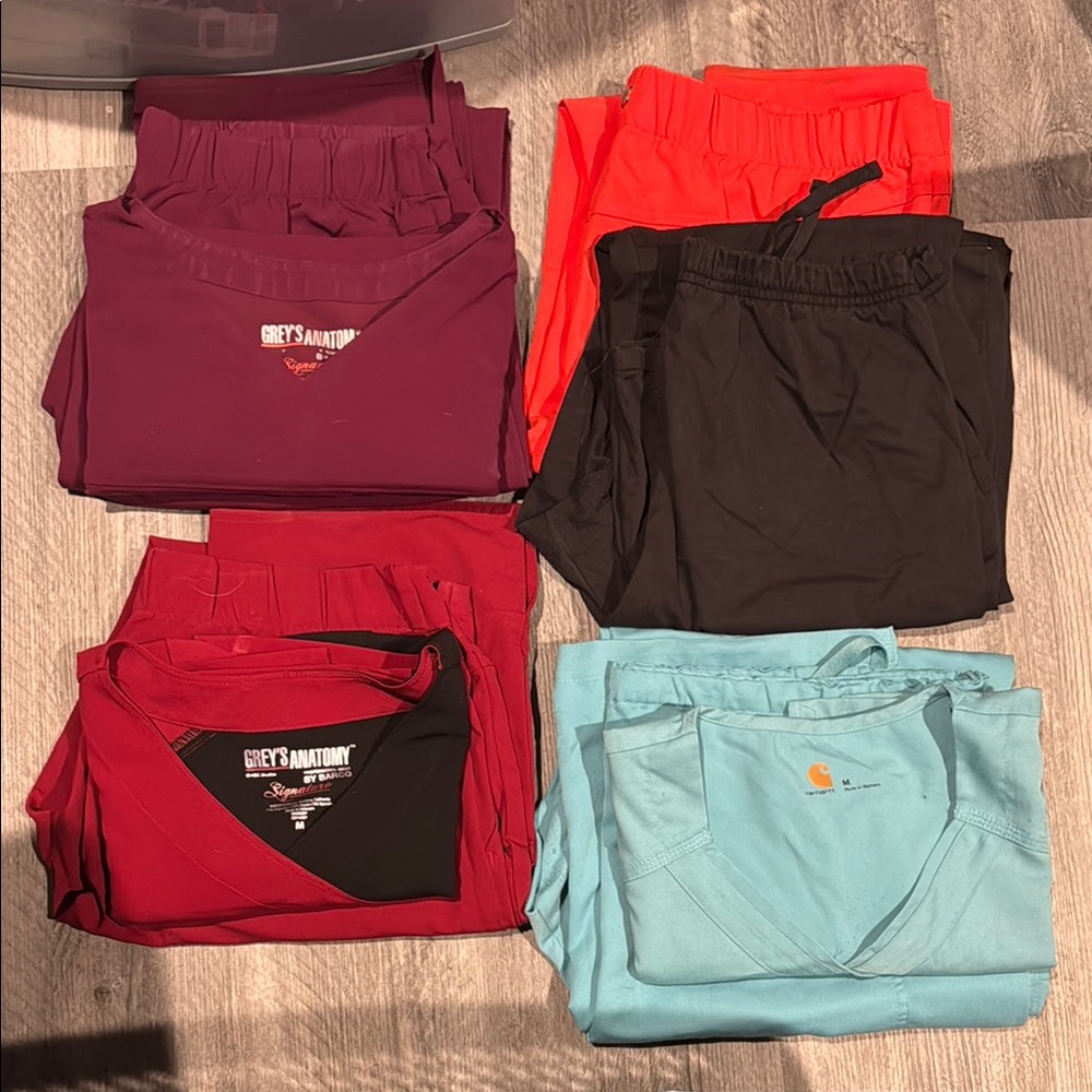 Various scrub sets Medium - Burgundy, Red/Black, and Light Blue.